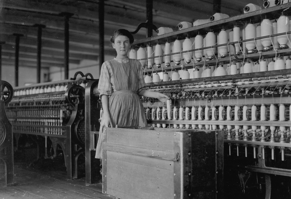 « Adrienne Pagnette, adolescente française analphabète, ne parle presque pas l’anglais. Est probablement âgée de 14 ou 15 ans. Salle de filature du dernier étage à Glenallen Mill. Son frère Francis a un travail régulier. Il a dit qu’il avait 15 ans, mais c’est peu probable. Sa sœur Anna a déclaré qu’elle avait 12 ans et qu’elle avait aidé sa sœur aînée à Glenallen Mill. J’y ai été tout l’été. Elle se tient à côté d’Adrienne sur la photo 2396 et sur la 2396A (fille plus grande). La photo 2396 montre toute la famille de 17 membres, dont 8 ou 10 travaillent dans l’usine. Presque tous sont analphabètes. Se pencher et pousser des boîtes lourdes est mauvais pour les jeunes filles adolescentes. » Winchendon, Massachusetts – septembre 1911 – LOC